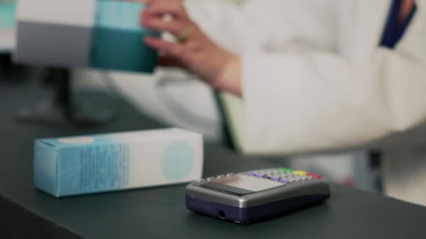 NFC付きスマートウォッチを薬の支払いに使用する若い女性は、ドラッグストアのレジに立っている。女性のクライアントは、 POS端末、薬局のデスクでサプリメントや薬を支払う。閉じろ!. - 映像、動画