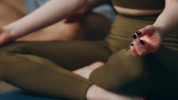 Femme inconnue assis position lotus avec jambes croisées sur tapis de sport de près. Jeune fille en vêtements de sport méditant à la maison pratiquant le yoga. Corps féminin faisant des exercices de respiration relaxante pour la santé. - Séquence, vidéo