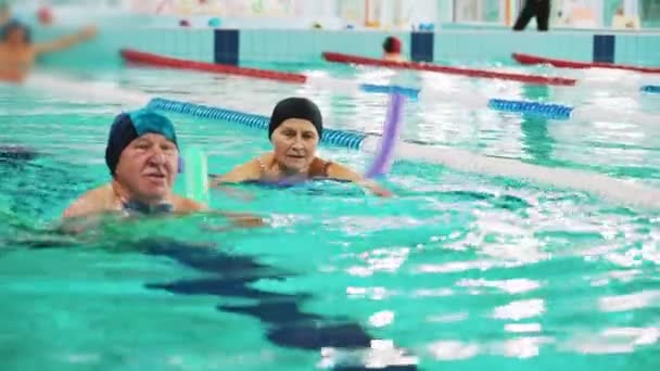 Additional swimming equipment. Side view of an elderly white man in a swimming cup, using green pool noodle. Active seniors. High quality 4k footage - Footage, Video