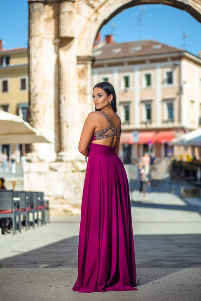 Beautiful black woman in a long red pink dress is walking in the old part of the city - Foto, Bild