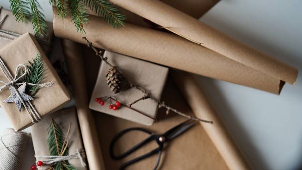 家庭や友人のためのクリスマスと新年の贈り物は、茶色の紙、ロープや自然植物の装飾、木の枝、コーン、ベリー、星に包まれています。選択的な焦点 - 写真・画像