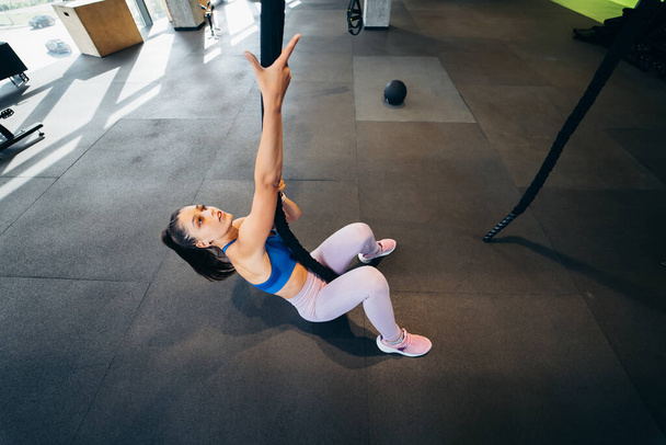 Jonge vrouw klimt een touw in de sportschool concept van sport. - Foto, afbeelding
