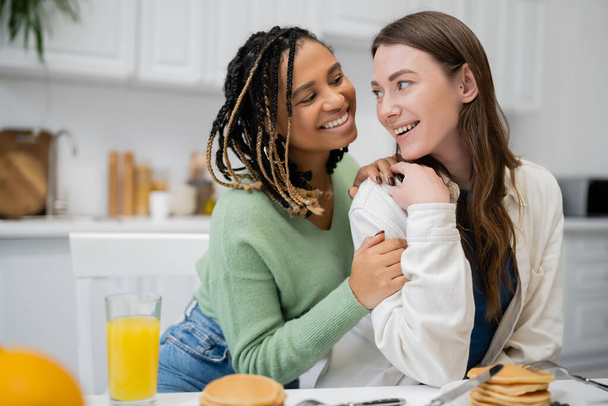 幸せとレズビアンアフリカ系アメリカ人女性抱擁笑顔ガールフレンドでキッチン  - 写真・画像