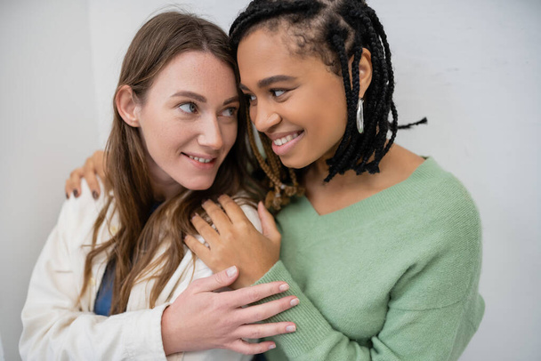 happy interracial and lesbian women smiling while hugging each other  - Foto, immagini