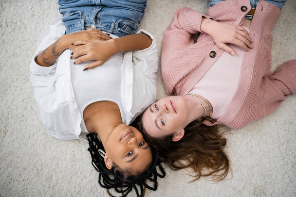 vue du haut du couple lesbienne heureux et multiethnique allongé sur un tapis mou  - Photo, image