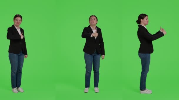 Businesswoman giving thumbs up over green screen studio backdrop, expressing like and approval on camera. Office worker in suit doing okay agreement gesture, acting positive and cheerful. - Footage, Video