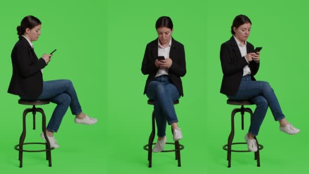 Moderni naismalli selailee internetiä älypuhelimella, toimii rennosti tuolilla studiossa. Yrityksen työntekijä puku käyttäen matkapuhelin app tekstiviestejä, koko kehon Greenscreen tausta. - Materiaali, video