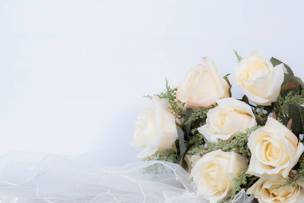 Top vista plana raio de anel de casamento, chapéu de noiva, grinalda, rosas e jóias no fundo branco com espaço de cópia / fundo de casamento ou conceito de aniversário - Foto, Imagem