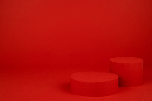 Due podi cilindro rosso mockup sul tavolo su ricco sfondo saturo per la presentazione di prodotti cosmetici, regali, merci in elegante stile moderno minimale, spazio copia. Modello per pubblicità, design. - Foto, immagini