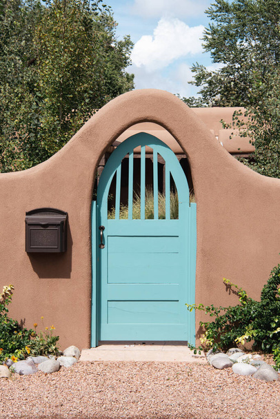 Turkoois poort in een gewelfde ingang van een tuin door een adobe muur in Santa Fe, New Mexico - Foto, afbeelding