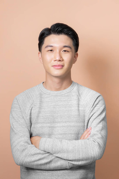 Young, handsome and friendly face man smile, dressed casually with happy and self-confident positive expression with crossed arms on beige background - 写真・画像