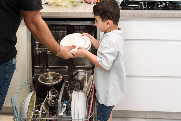 Hijo ayudando a papá con el lavavajillas. Concepto de tareas. - Foto, Imagen