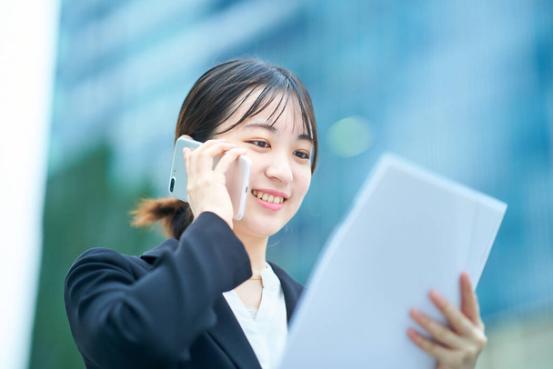 Asiatique jeune femme dans un costume parler sur un smartphone - Photo, image