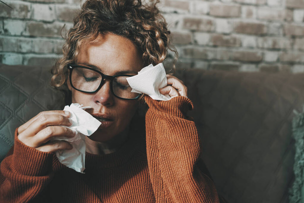 Portrait of woman in bad health condition using tissues and touching front for headache. Flu virus influenza with fever symptoms in young adult female people at home. Concept of bad health winter - Фото, изображение