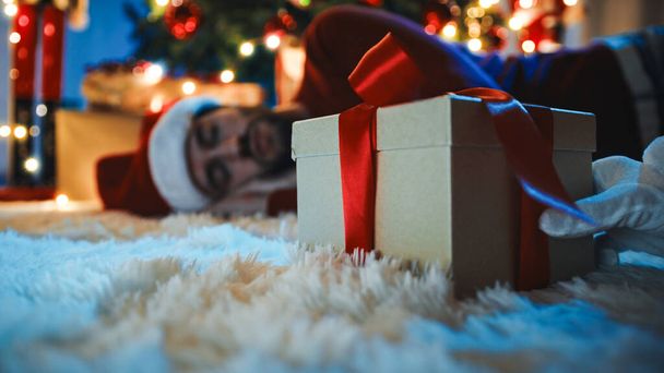 Man Sleeps By Christmas Gift Box wait for the santas gift box. - Foto, afbeelding