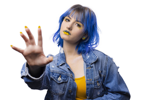 Portrait of young stylish woman posing indenim jacket, blue and yellow tones of clothes in Ukrainian colors style, lady on white isolated background, flowers art on lips - Φωτογραφία, εικόνα