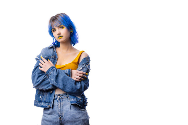 Portrait of young stylish woman posing indenim jacket, blue and yellow tones of clothes in Ukrainian colors style, lady on white isolated background with copy space - 写真・画像