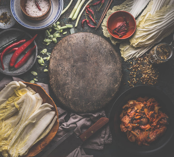 Kimchi cooking preparation with ingredients: chinese cabbage , chili, spices and salt around round rustic cutting board, top view. Frame. Healthy  fermented food - Photo, image