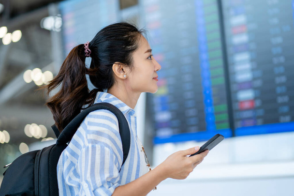 Ázsiai női utazó ellenőrzi a járatokat a nemzetközi repülőtéren hétvégén kirándulás - Fotó, kép