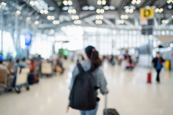 Wazig beeld van gelukkige Aziatische vrouw met rugzak en bagage op de internationale luchthaven. Achtergrondbeeld. - Foto, afbeelding