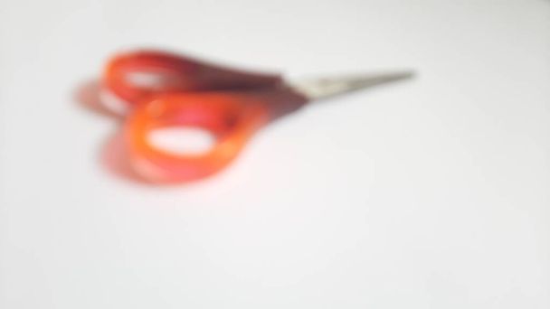 Ciseaux simples flous ou flous ou déconcentrés ou un ciseau brun orangé rouge sur fond blanc isolé - Photo, image