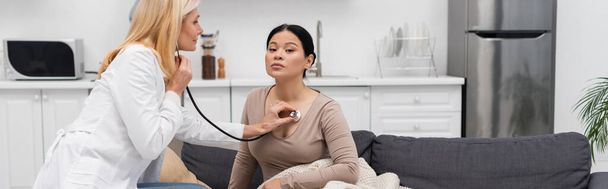 Middle aged doctor checking lungs of patient with stethoscope at home, banner  - Photo, Image