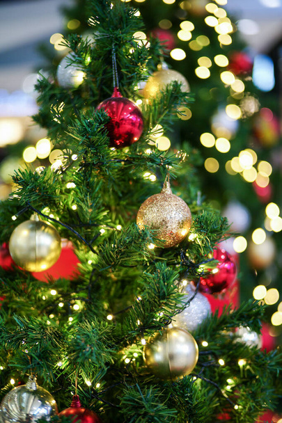 Focus sélectif sur la boule dorée décorée sur le sapin de Noël avec les lumières bokeh en arrière-plan. Fête et célébration au festival de Noël - Photo, image