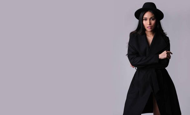 Модна брюнетка азіатська етнічність у стильному чорному пальто та капелюсі сірий фон
. - Фото, зображення