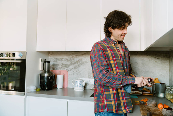 White man wearing shirt cutting vegetables while cooking lunch in kitchen at home - Photo, Image