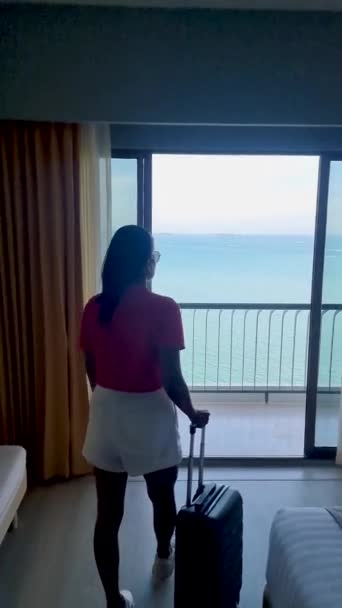 Aziatische vrouwen met handbagage inchecken in een hotel in Thailand met uitzicht op de tropische oceaan.  - Video