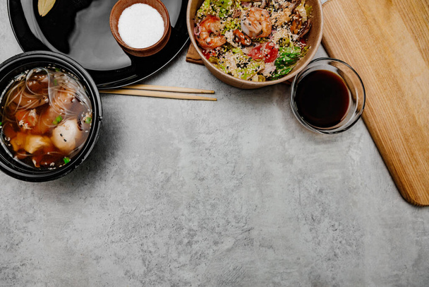 Sopa de udon de camarão, salada de frutos do mar e tigela de molho de soja no fundo cinza. Vista de cima - Foto, Imagem