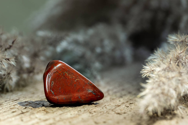 Red Jasper Tumbled Gem Stone на сайті Wooden Background Яспер використовується для прикраси або як самоцвіт - Фото, зображення
