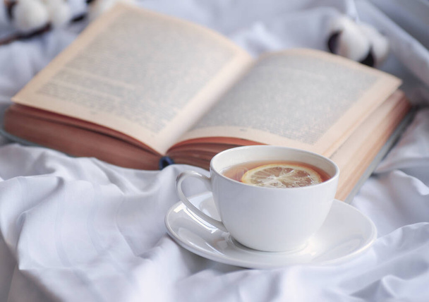 mug of hot tea and book - 写真・画像