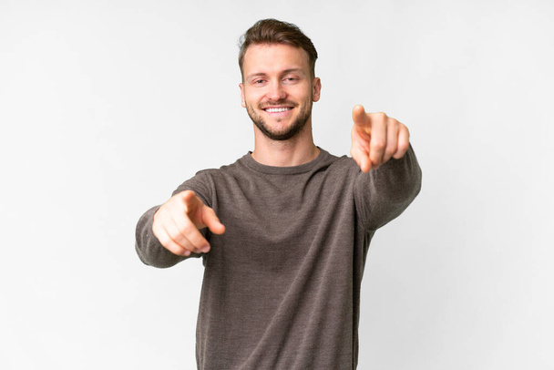 Young handsome caucasian man over isolated white background pointing front with happy expression - Photo, image