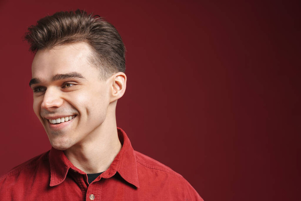 Young white man wearing shirt smiling and looking aside isolated over red background - Photo, Image