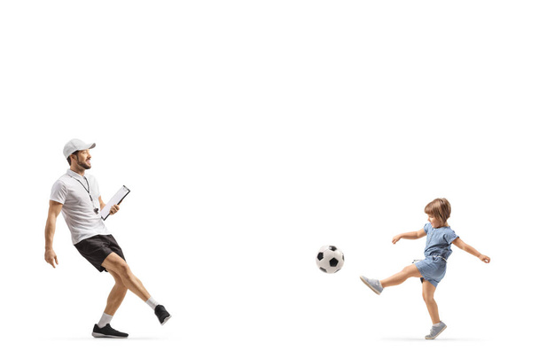 Coach with a whistle holding a clipboard and kicking a ball with a little girl isolated on white backgroun - Foto, Imagen