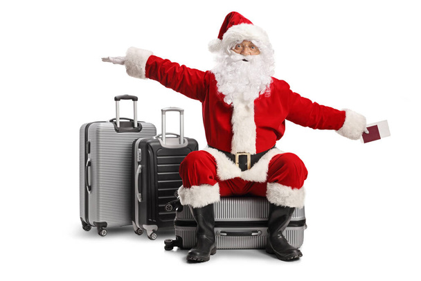 Santa claus sitting on a suitcase and flying with hands isolated on white background - Фото, зображення