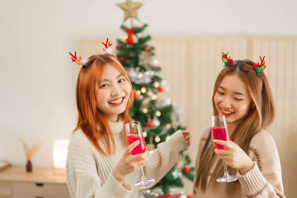 Koncepcja dekoracji świątecznej, Dwie kobiety piją szampana i tańczą w pobliżu choinki. - Zdjęcie, obraz