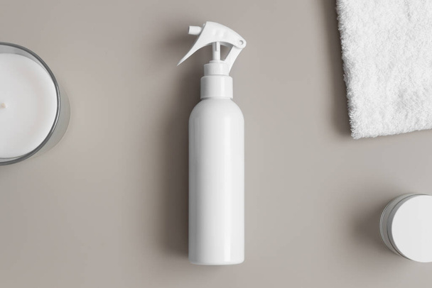 Белый косметический макет бутылки распылителя с полотенцем на бежевом столе. - Фото, изображение