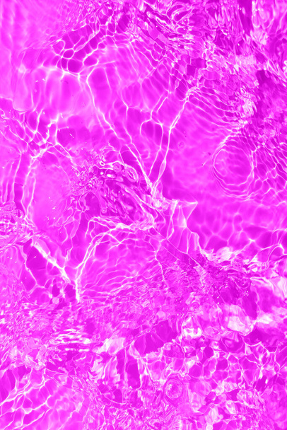 Defocus blurred transparent purple colored clear calm water surface texture with splashes and bubbles. Trendy abstract nature background. Water waves in sunlight with copy space. Pink water drop shine - Photo, Image