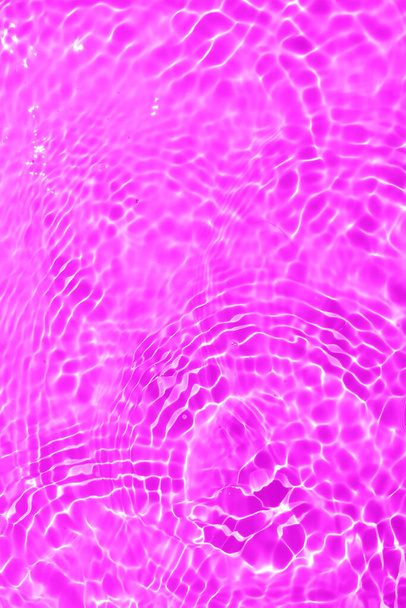 Defocus elmosódott átlátszó lila színű tiszta, nyugodt vízfelület textúra fröccsenések és buborékok. Trendi elvont természet háttér. Vízhullámok a napfényben fénymásolási hellyel. Rózsaszín vízcsepp ragyog - Fotó, kép