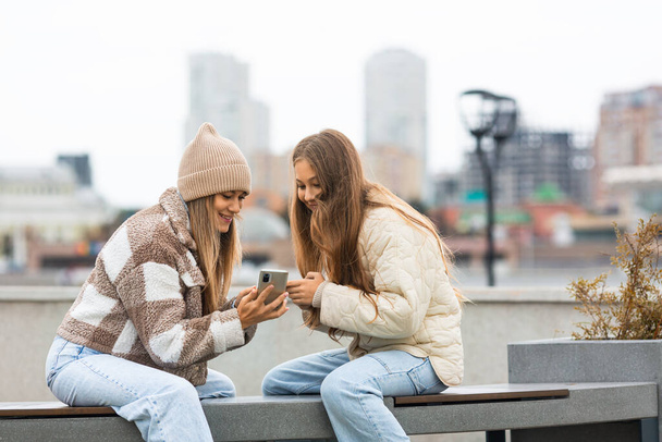 Bizalom és megértés generációk között - anya és lánya együtt töltik a szabadidejüket a szabadban, okostelefonokkal nézik egy okostelefonok képernyőjét, megosztják a fényképet, tartalmat mutatnak. - Fotó, kép
