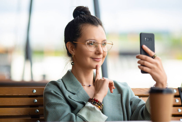 Zbliżenie zdjęcia 35-letniej kobiety ze smartfonem podczas rozmowy wideo online. - Zdjęcie, obraz