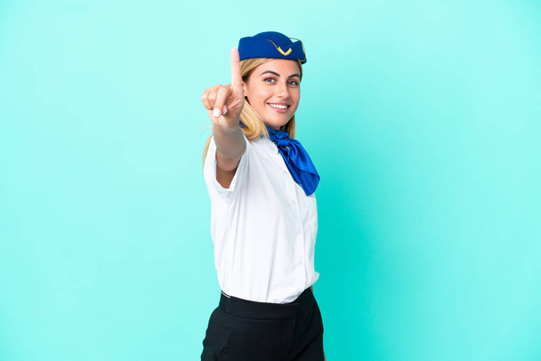 Αεροσυνοδός Ουρουγουανή γυναίκα απομονωμένη σε μπλε φόντο που δείχνει και σηκώνει το δάχτυλό της - Φωτογραφία, εικόνα