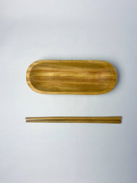 Flat lay of empty wooden oval plate for sushi or other food and wooden chopsticks on white background. - Photo, Image
