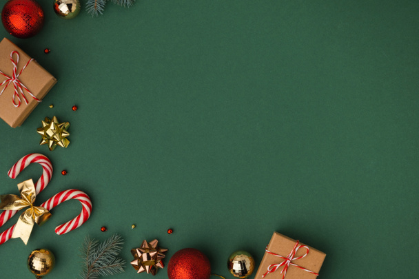 Kerst achtergrond met kartonnen geschenkdozen, snoep stokken en gouden kerstboom speelgoed. Feestelijk gevoel van komende feestdagen. Donkergroene achtergrond met kopieerruimte voor een begroeting tekst. Vlakke plaat - Foto, afbeelding