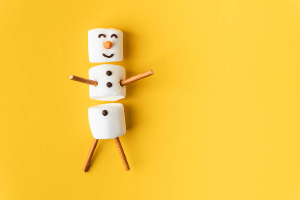 Buon divertente pupazzo di neve marshmallow sullo sfondo giallo. Piatto. Copia spazio per un testo libero. Anticipazione del Natale. Concetto invernale sfondo. - Foto, immagini