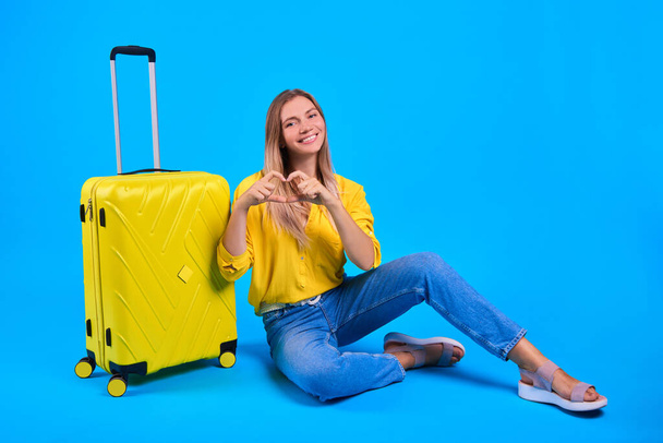 concept van langverwachte reis. Ik hou van reizen en reizen. Op vakantie. vrouw met gele koffer op blauwe achtergrond. - Foto, afbeelding