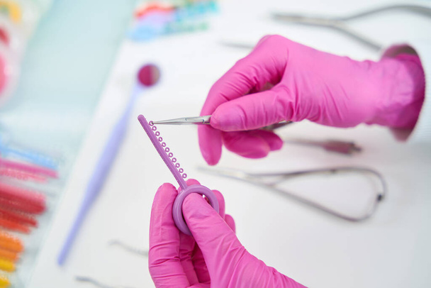 Doktor zubař strhne lešticí kotouč z běžné palety s pinzetou, specialista na ochranné rukavice - Fotografie, Obrázek