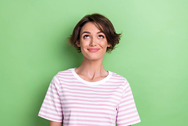 Photo of optimistic bob hairdo millennial lady look up wear white striped t-shirt isolated on green color background. - Zdjęcie, obraz
